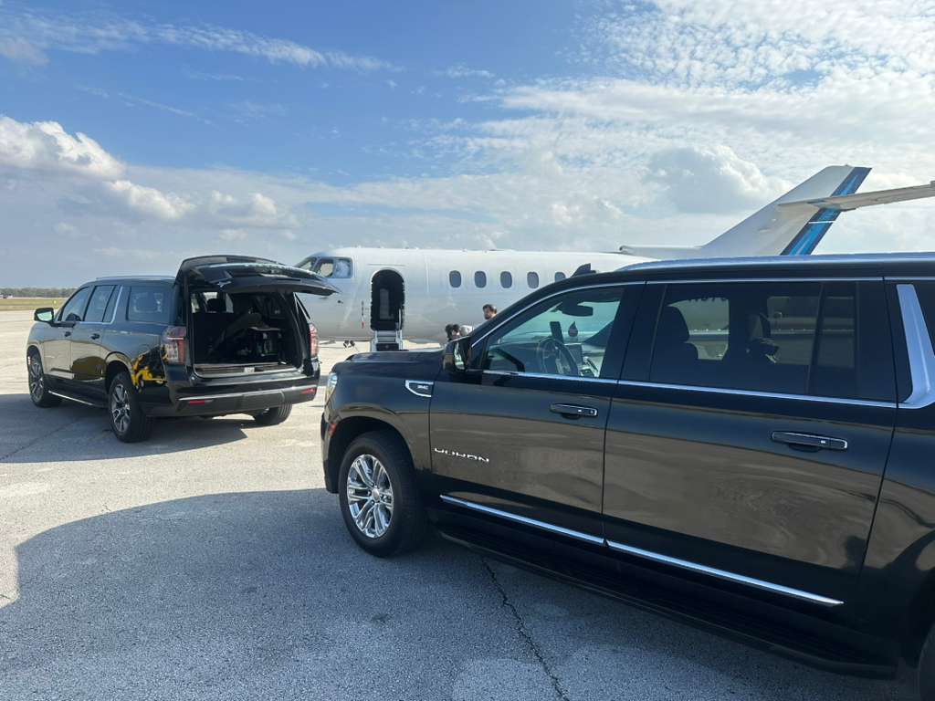 Luxury SUVs positioned on the tarmac beside a private jet